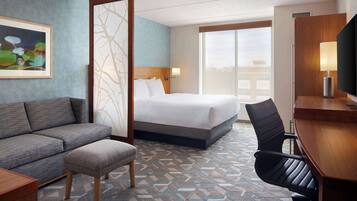 Quarto de hotel com cama, sofá, escrivaninha e cadeira.