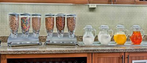 Una zona de cocina con dispensadores de cereales varios y una selección de jarras con diferentes bebidas.