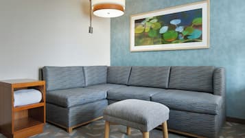 A modern living room with a sectional sofa, a wooden nightstand, and a gray ottoman.