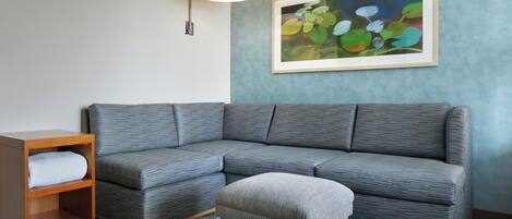 A modern living room with a sectional sofa, a wooden nightstand, and a gray ottoman.