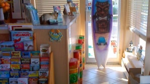 A small shop with various items on shelves and a surfboard decoration. - Granada Ocean Resort (Wildwood Crest)