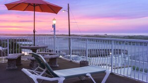 A balcony with a red umbrella, outdoor seating, and a view of the water. - Granada Ocean Resort (Wildwood Crest)