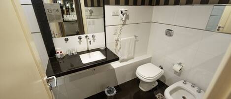Un baño moderno con encimera negra, lavabo y váter blancos, y un bidé.
