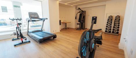 Un gimnasio moderno con cintas de correr, bicicletas estáticas y una máquina de remo.