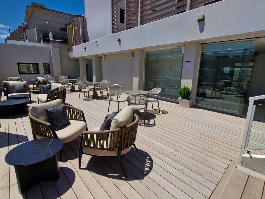 An outdoor patio with wicker furniture, a marble table, and a potted plant.