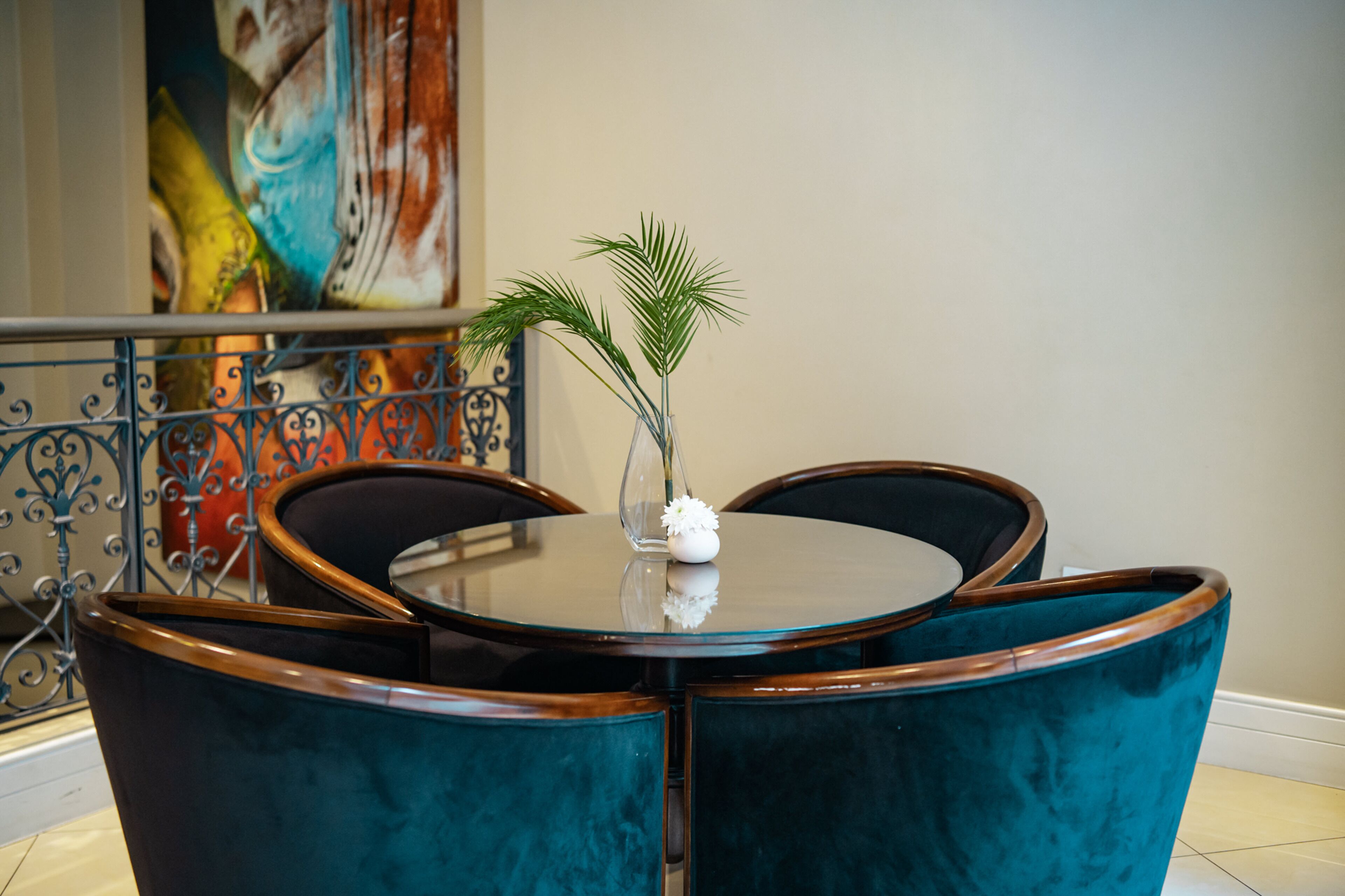 A round table with a glass top and a vase with a flower.
