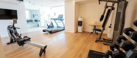 Un gimnasio moderno con máquinas de cardio, pesas libres y una cinta de correr.