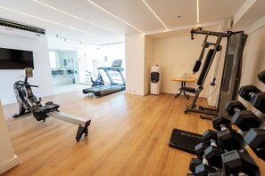 Un gimnasio moderno con máquinas de cardio, pesas libres y una cinta de correr.