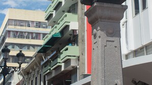 A clock tower with a clock face, surrounded by buildings with balconies and a clear sky. - Hotel El Maragato (San José)