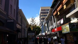 A busy urban street with various shops and a casino. - Hotel El Maragato (San José)