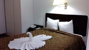 A hotel room with a bed, a nightstand, a lamp, and a wall-mounted light fixture. - Hotel El Maragato (San José)