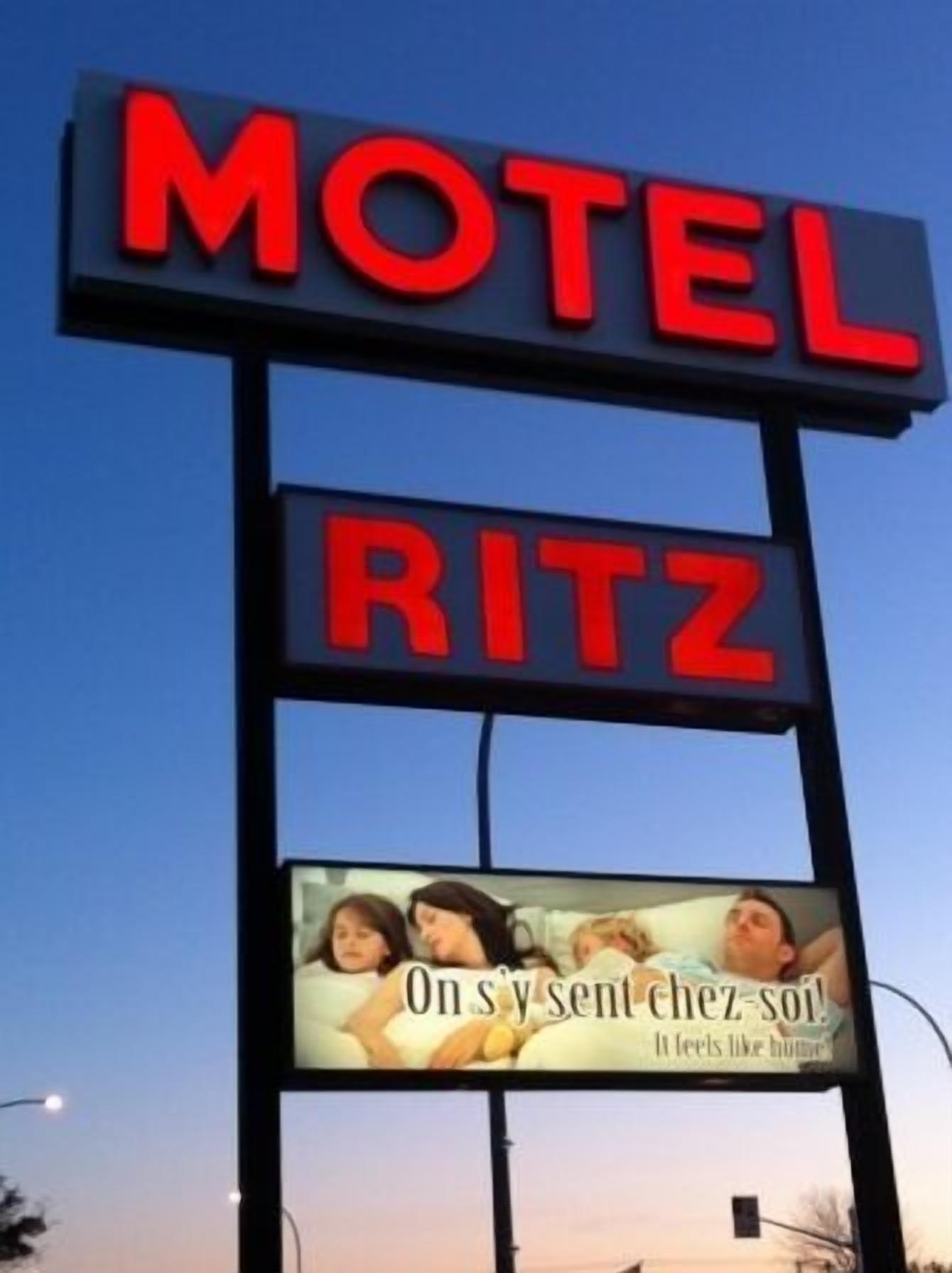 A motel sign with the name 'MOTEL RITZ' and an advertisement below featuring a family.