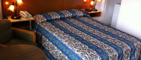Een hotelkamer met een bed, een stoel, een nachtkastje met lamp en een telefoon.