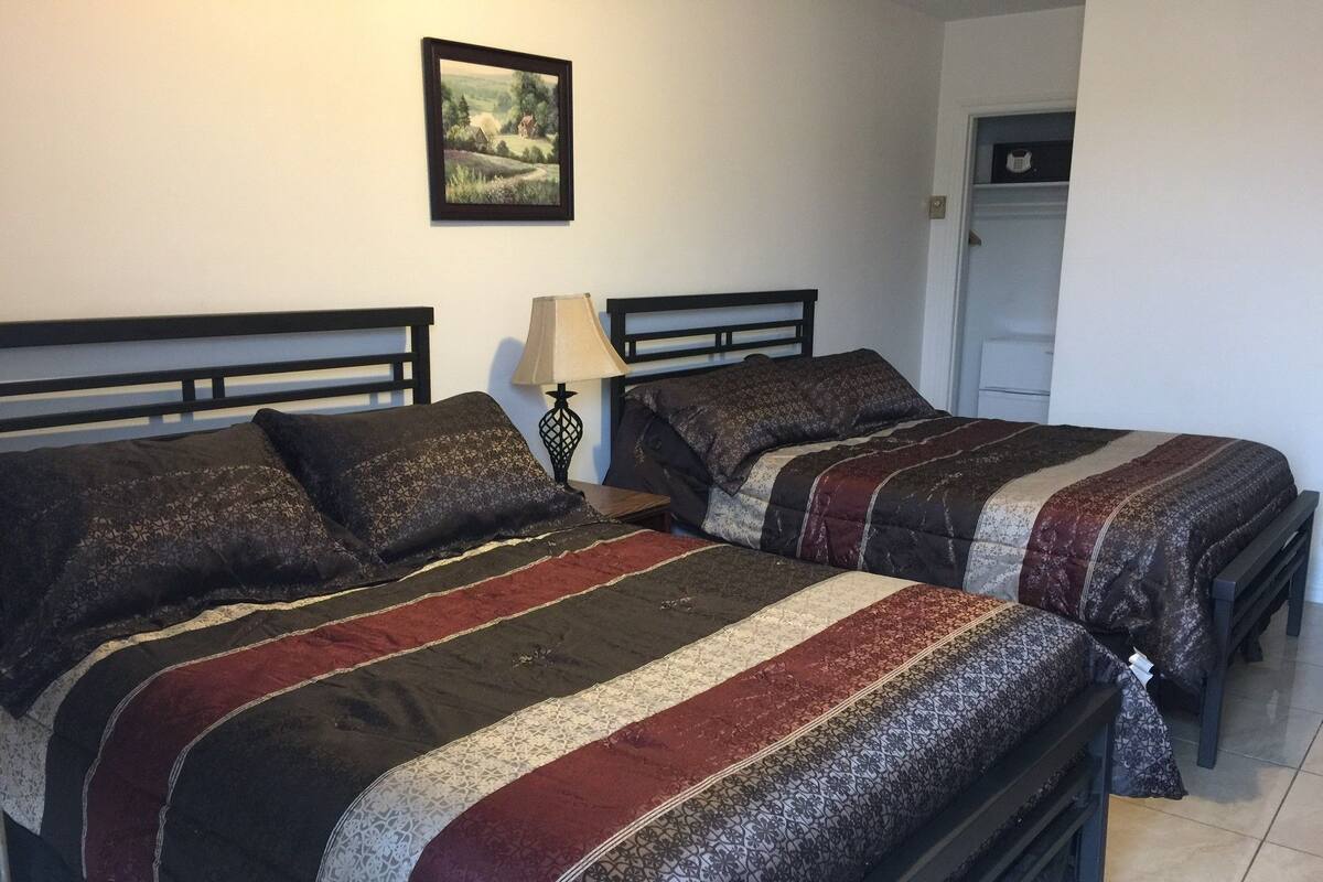 A bedroom with two beds, each with patterned bedding and a nightstand with a lamp.