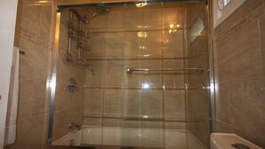 A glass-enclosed shower with a glass door, a bathtub, and a toilet. - Motel Ritz (Gatineau)