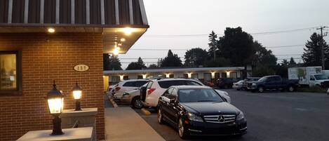 A building with a brick facade, a number '137' sign, and a row of parked cars including a black Mercedes-Benz.