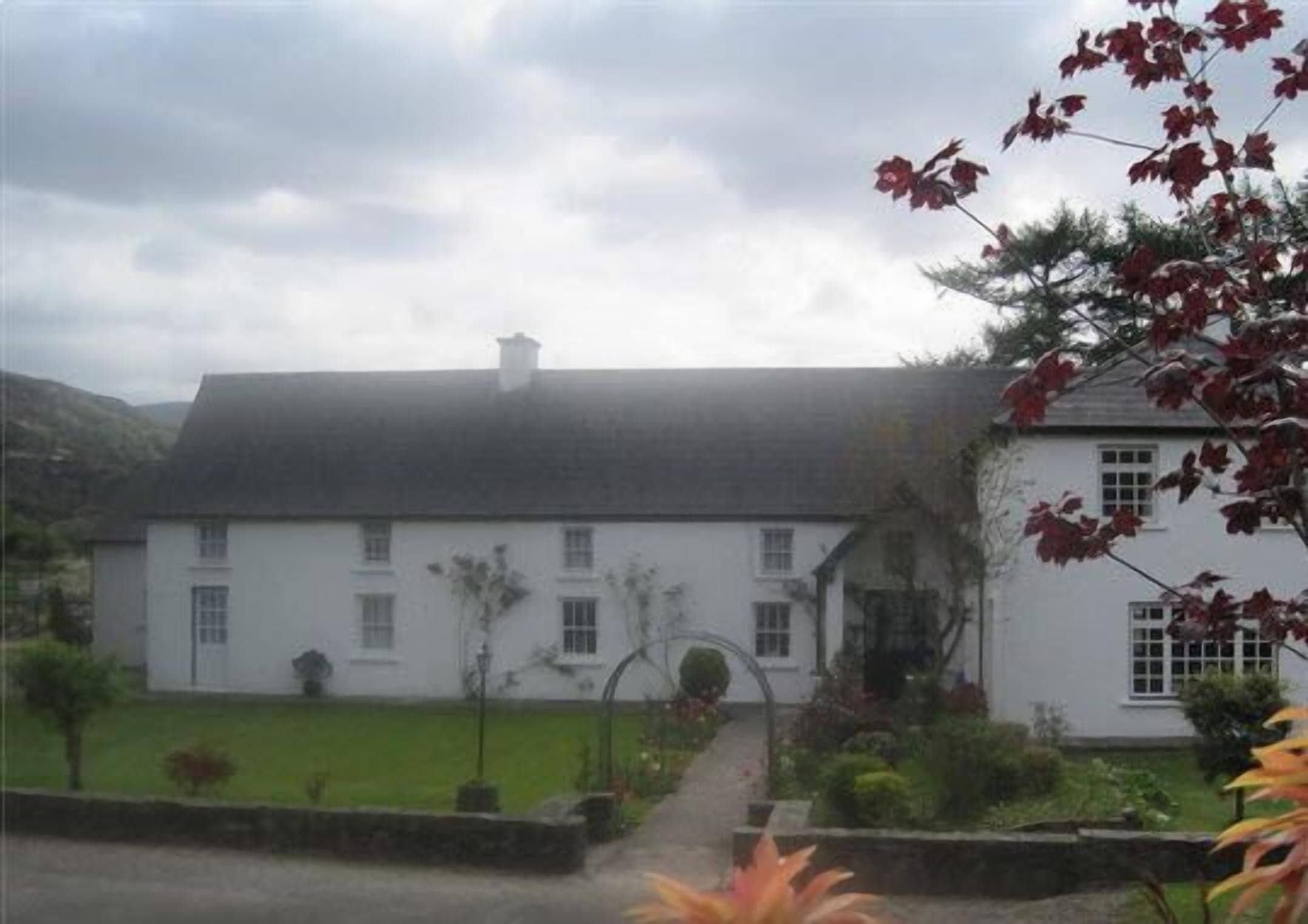 A white two-story house with a symmetrical facade, a central entrance, and a well-maintained garden.