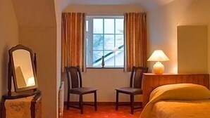 A hotel room with a bed, two chairs, a window with curtains, a lamp, and a mirror. - Salmon Leap Farm B&B (Killarney)