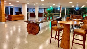 A modern hotel lobby with a central wooden bar, seating areas, and a reception desk. - Hotel Amazônico (Belém)