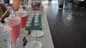 A buffet setup with various food items and drinks, including a fruit salad and a red beverage, arranged on a table with plates and cutlery. - Hotel Amazônico (Belém)
