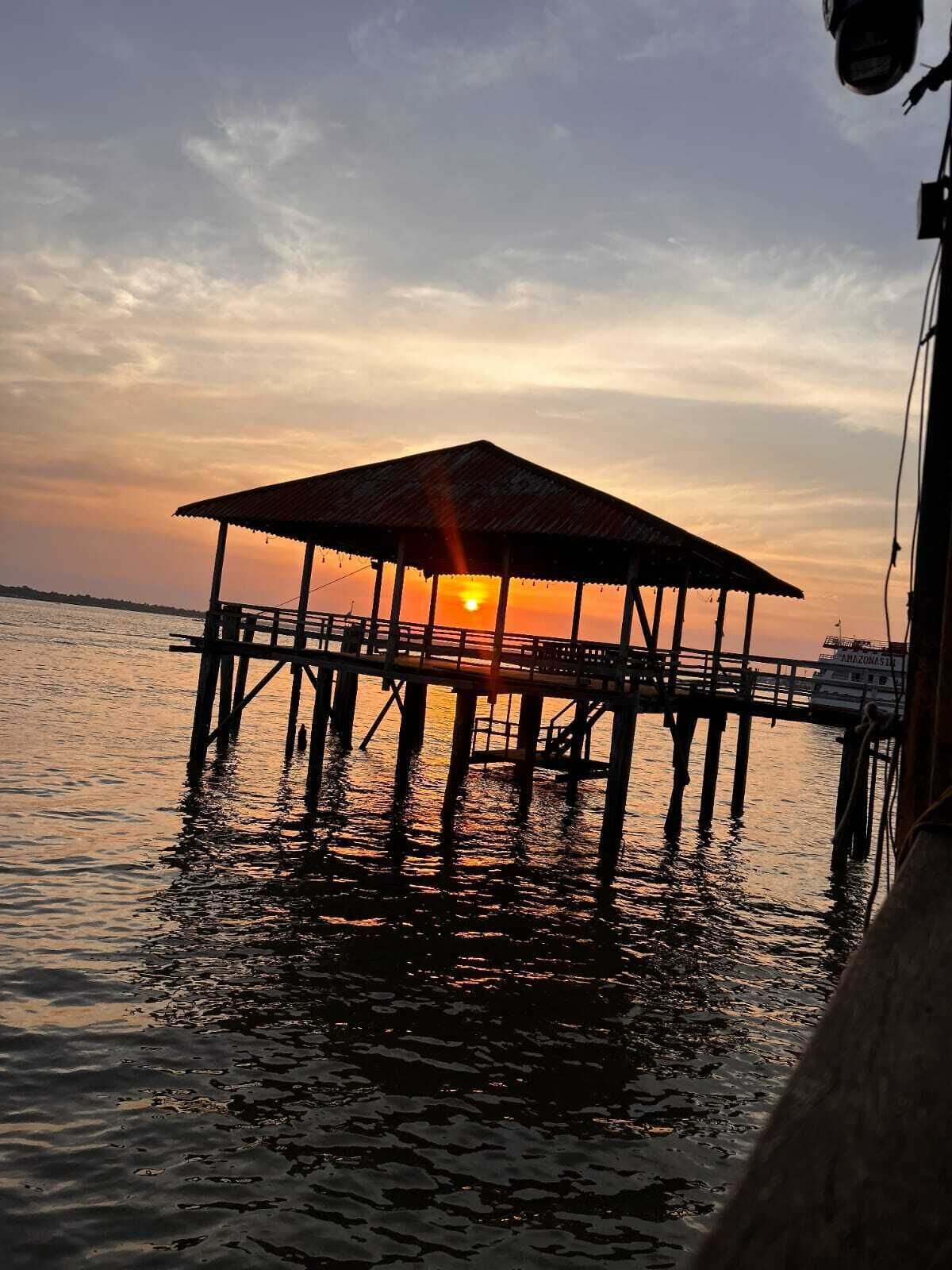 A pier with a covered structure at sunset.