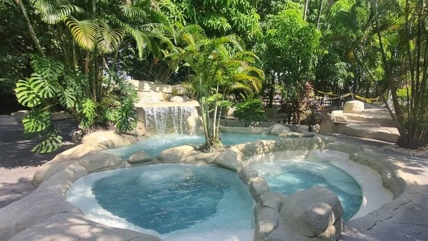A hot spring area with multiple pools and a waterfall, surrounded by lush greenery. - Hotel Amazônico (Belém)