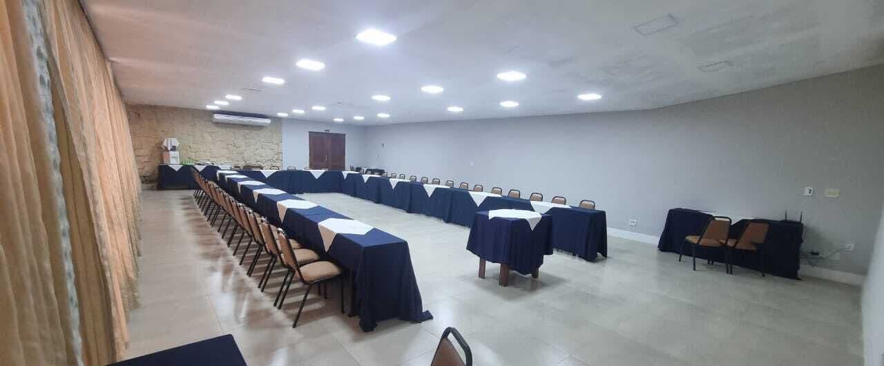 Una sala de conferències amb files de taules i cadires, una paret de pedra i una porta.