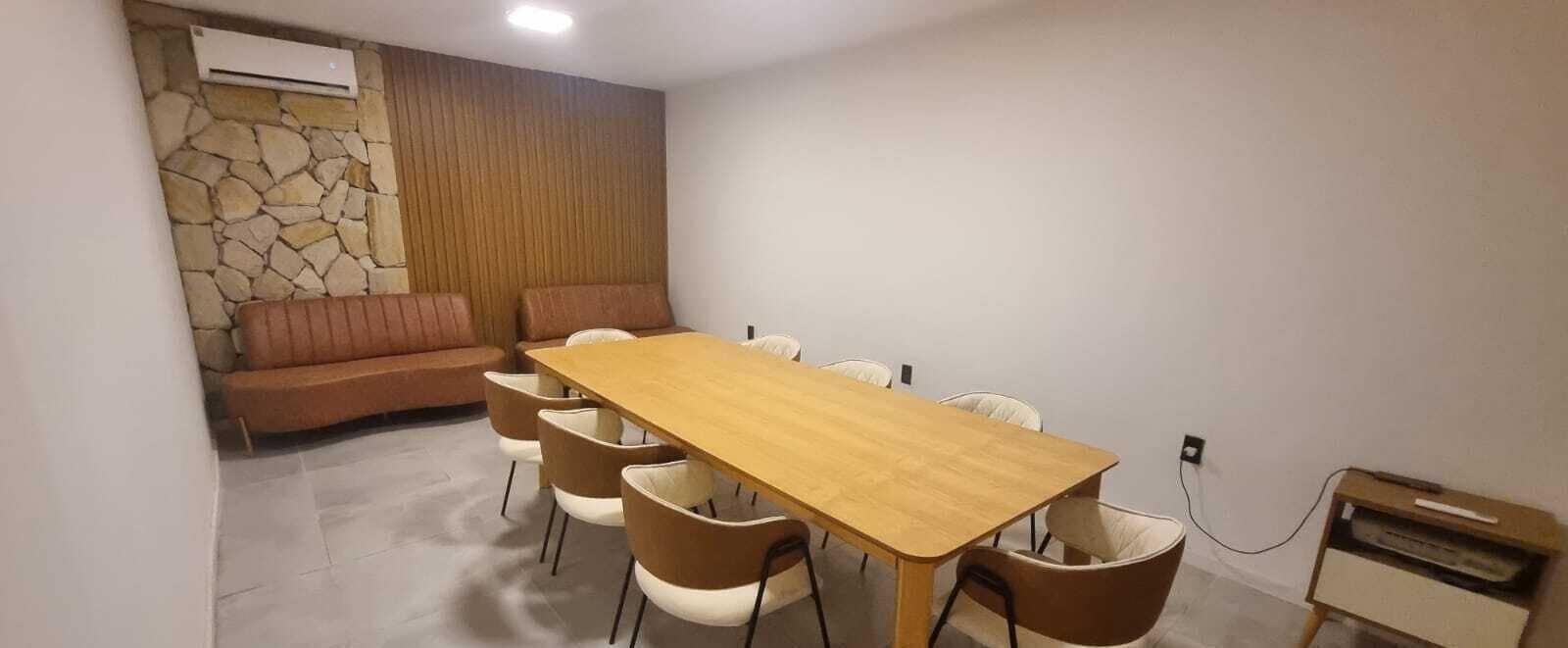 A dining area with a wooden table and six chairs, a stone wall, and a wooden panel wall.