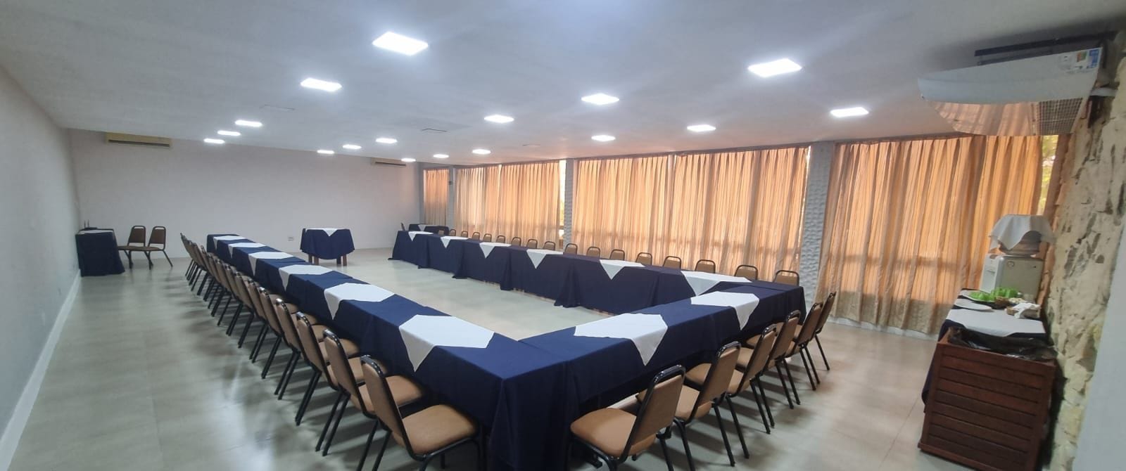 Uma sala de conferências com uma mesa comprida, cadeiras e um amplo janela com cortinas.