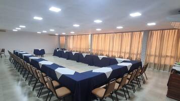 Uma sala de conferências com uma mesa comprida, cadeiras e um amplo janela com cortinas.