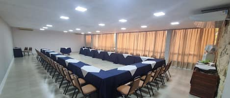 A conference room with a long table, chairs, and a large window with curtains.