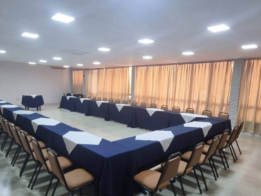 Uma sala de conferências com uma mesa comprida, cadeiras e um amplo janela com cortinas.