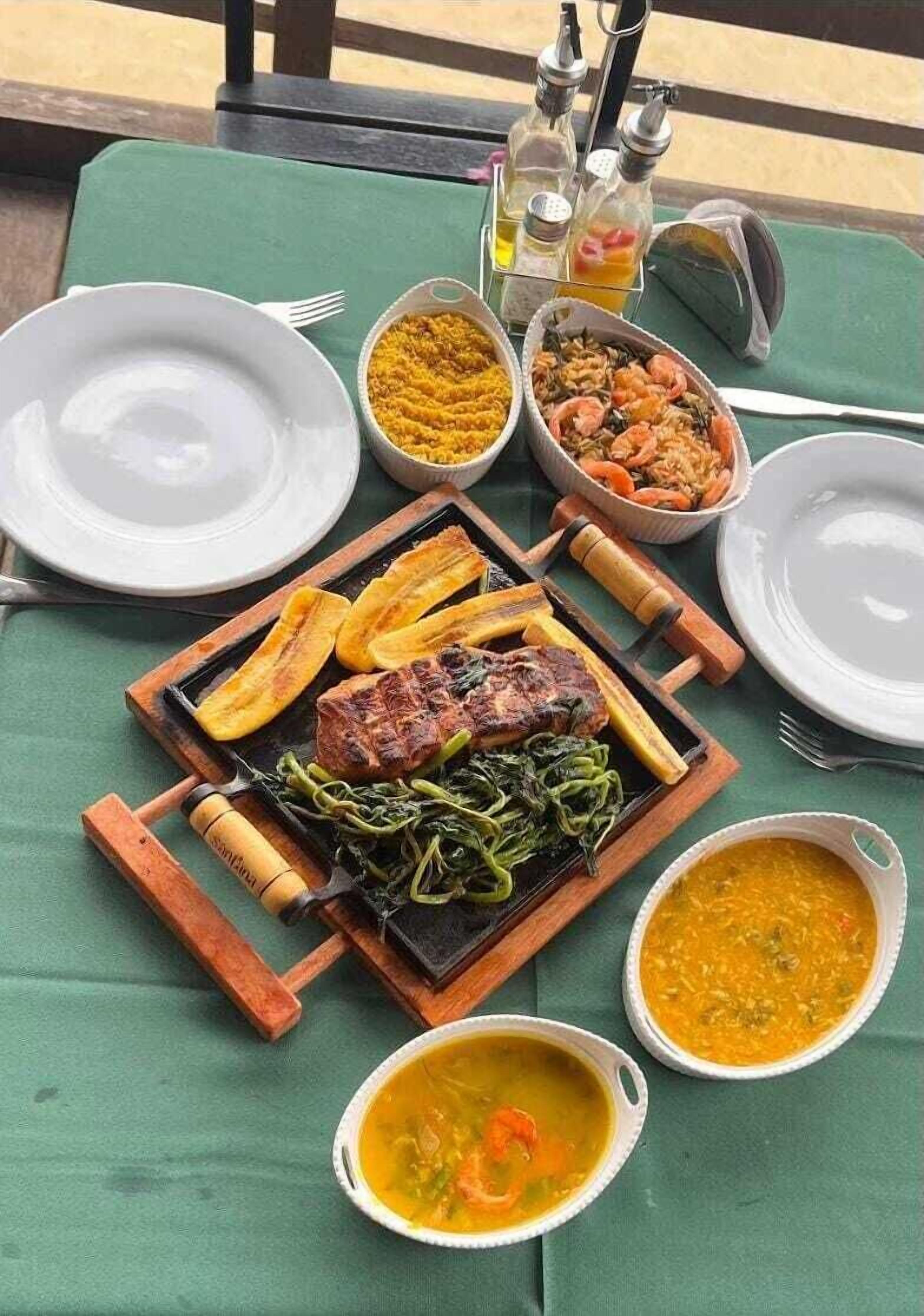 Una tavola imbandita con diversi piatti, tra cui carne alla griglia, verdure e zuppe servite in ciotole.
