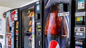 Een automaat met Coca-Cola en Pepsi logo's en diverse snacks.
