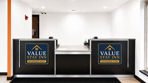Un comptoir d’accueil doté de deux guichets, chacun affichant une enseigne indiquant « Value Stay Inn Extended Stay ».