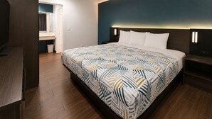Une chambre d’hôtel moderne, dotée d’un grand lit, d’un bureau et d’une salle de bain visible à travers une porte ouverte.