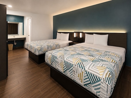 A hotel room with two beds, a bathroom, and a view of the outside.