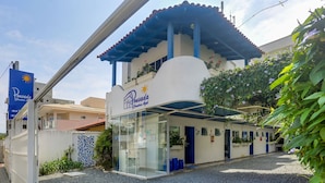 A building with a blue and white facade, a covered entrance, and a sign reading "Pousada Canaria Azul". - Pousada Canário Azul (Bombinhas)