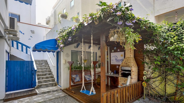 A small outdoor café with a brick oven, wooden seating, and hanging plants. - Pousada Canário Azul (Bombinhas)