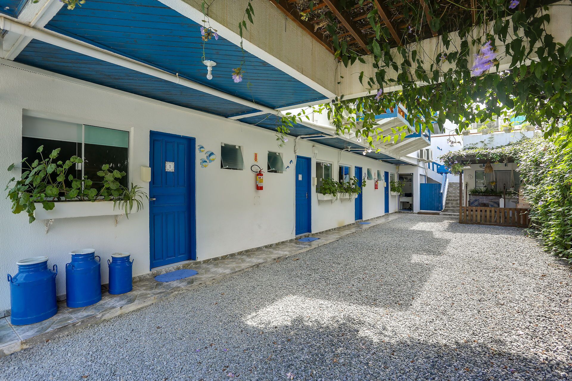 Una estrecha calle empedrada con una hilera de edificios blancos con puertas y ventanas azules.