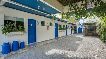 Una estrecha calle empedrada con una hilera de edificios blancos con puertas y ventanas azules.