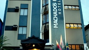 A modern hotel building with a prominent sign reading "Machados Plaza Hotel".