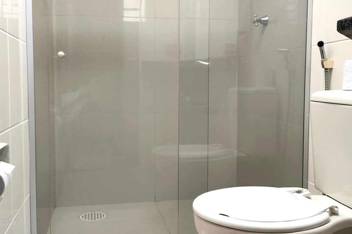 Un baño moderno con ducha de vidrio, inodoro blanco y toallero a la vista.