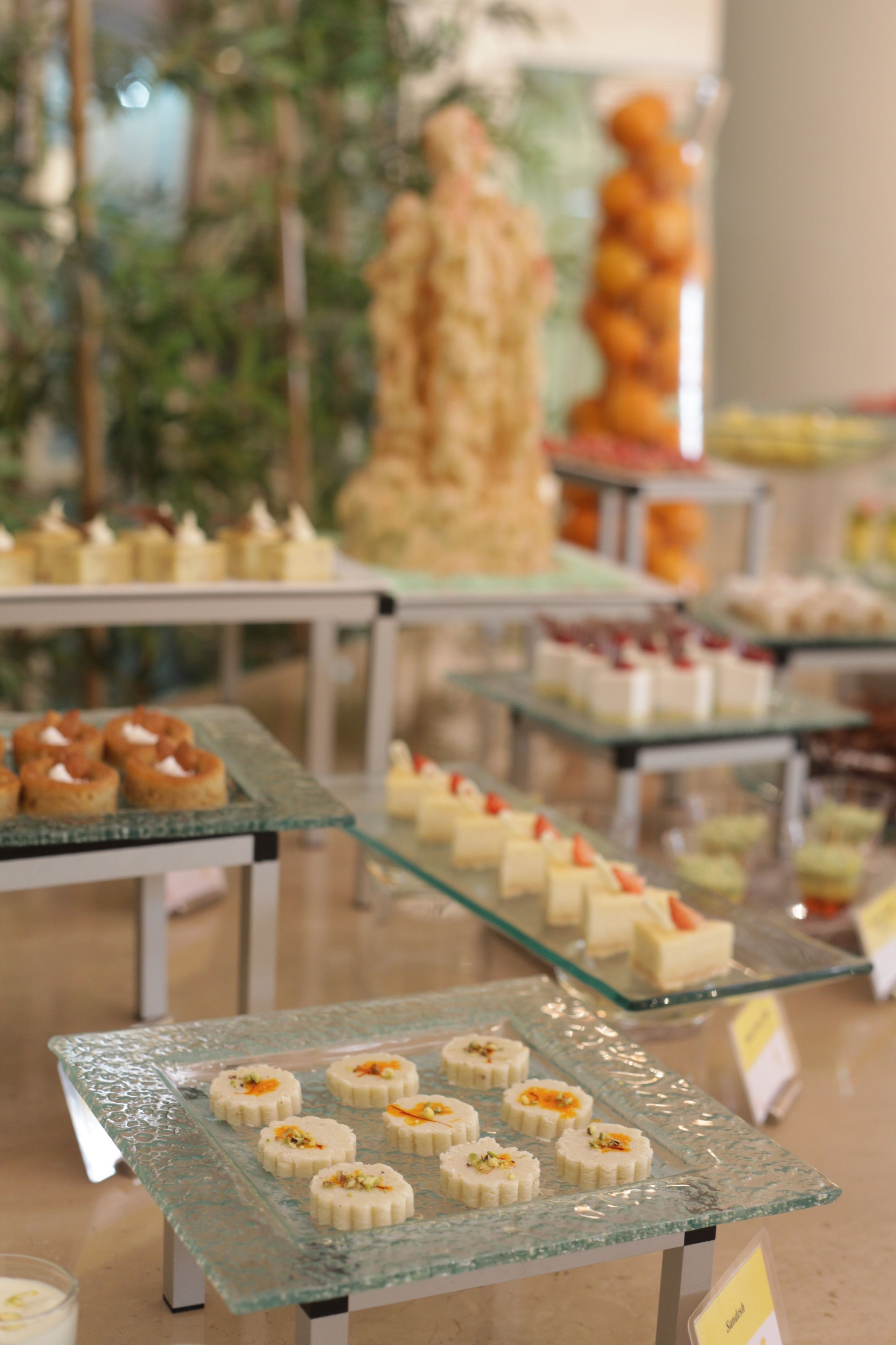 A buffet with various desserts on glass serving trays.