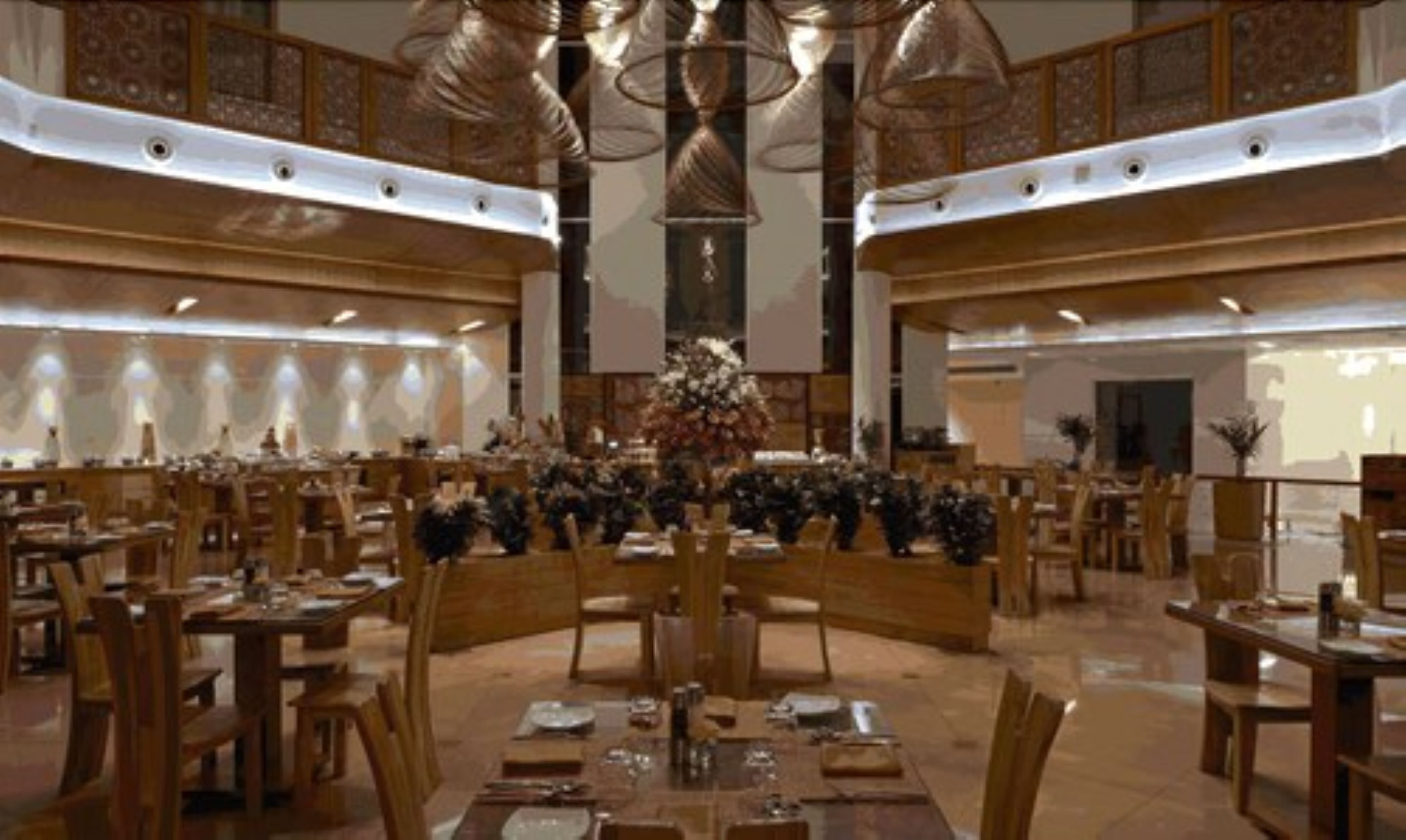 A spacious dining area with multiple tables and chairs, a central floral arrangement, and a high ceiling with decorative lighting.