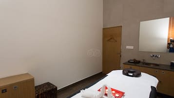 Relax in a serene space with a neatly made bed, wooden wardrobe, and a large mirror.