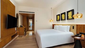 A modern hotel room with a large bed, a flat-screen TV, a desk with a phone, and artwork on the wall.