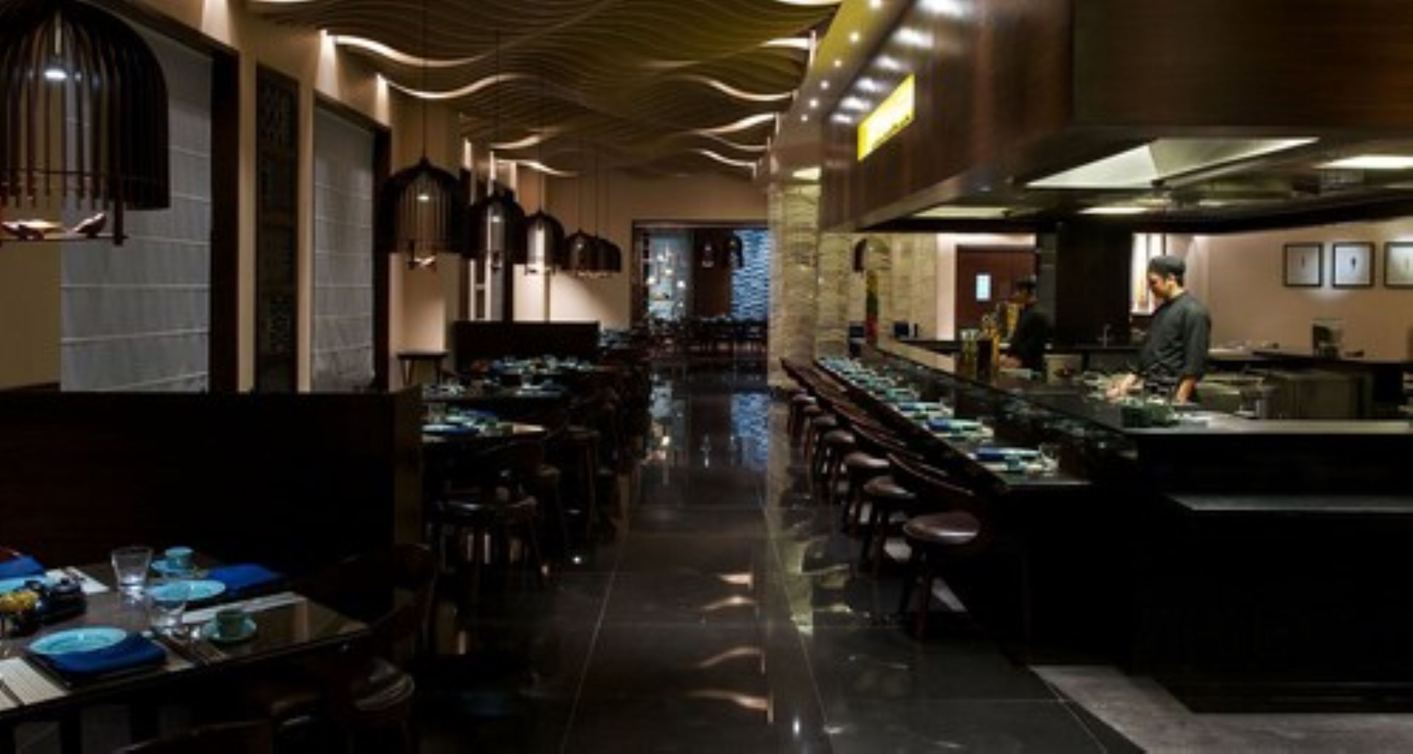 Ein Restaurant mit einer langen Theke, mehreren Tischen und einem modernen Interieur.