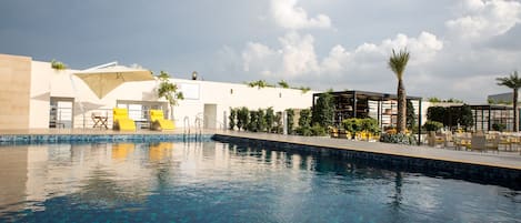 Una piscina con agua azul cristalina, rodeada de mobiliario exterior y palmeras.