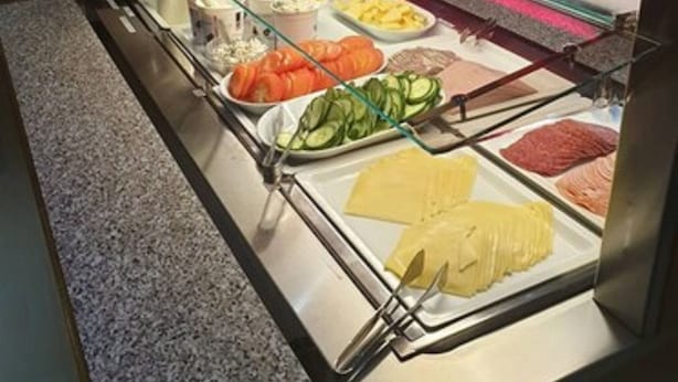 Ein reichhaltiges Buffet mit verschiedenen Speisen, darunter geschnittenes Gemüse, Fleisch und Käse.